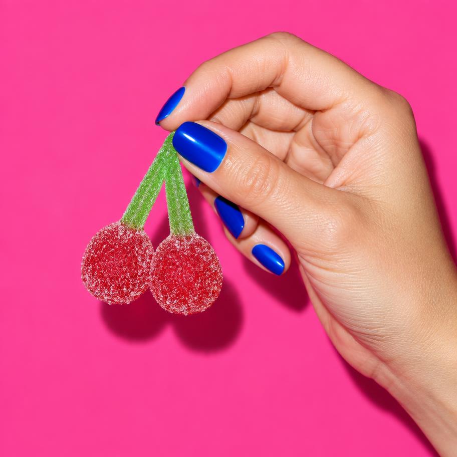 Blue-polished hand holding fizzy cherries